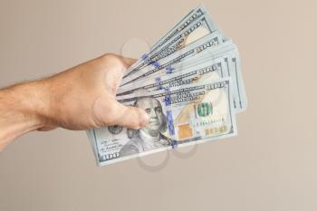 100 Dollars notes in male hand over gray background