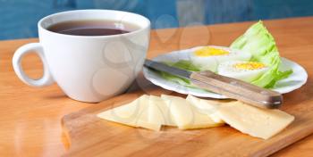 Simple breakfast background with black tea cup, cheese and boiled egg