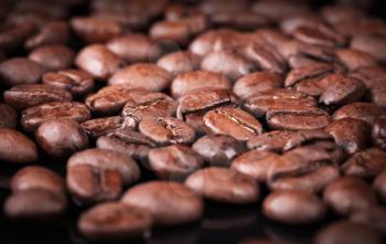 Fresh roasted coffee beans on black table. Closeup photo with selective focus