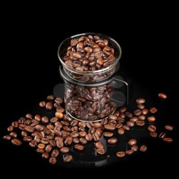 Mug made of glass with whole roasted coffee beans on black background