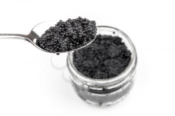 Black caviar in full glass jar and teaspoon isolated on white background