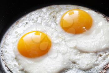 Closeup photo of two scrambled eggs in black frying pan