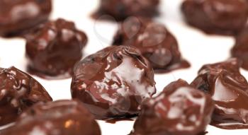 Homemade prunes in chocolate candies on white table background