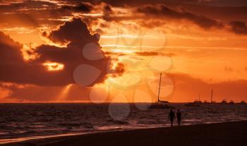 Coastal Caribbean seascape at sunrise. Atlantic ocean coast, sandy beach in red morning sunlight