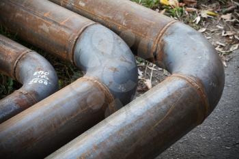 Bend of industrial steel pipeline over asphalt urban road
