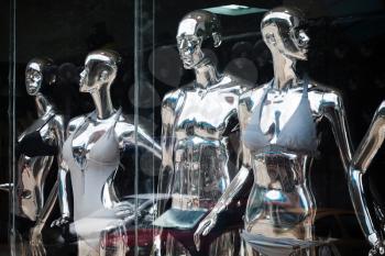Shining metallic mannequins standing in a clothes shop window