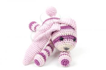 Knitted pink rabbit toy lays isolated on white background, selective focus with shallow DOF