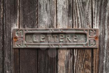 Old rusted mailbox in dark brown wooden door. Text Lettere in Italian means Letters
