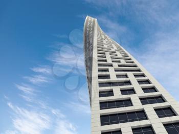 Abstract modern architecture. Twisted office tower perspective over blue cloudy sky. 3d render illustration