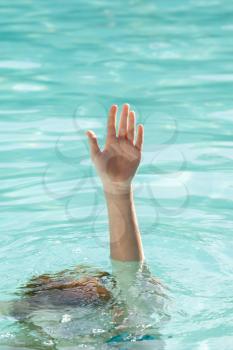 Hand of a drowning person stretching out of sea water pool and asking for help