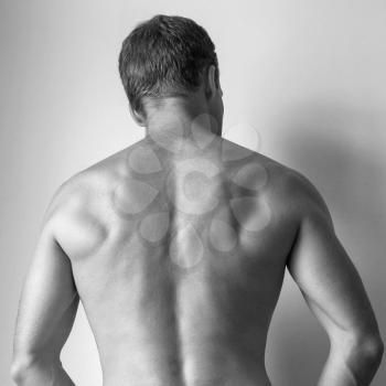 Back of Strong young Caucasian man, black and white studio photo