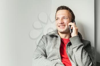 Portrait of sitting young Caucasian man talking on mobile phone