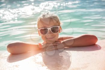 Beautiful little blond girl with sunglasses in outdoor pool, closeup bright summer portrait, colorful  toned photo, old style instagram filter effect