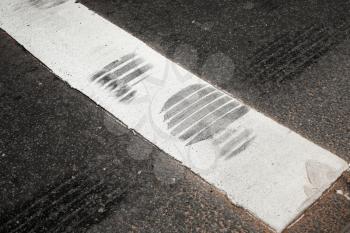 Pedestrian crossing fragment with white stripe and tire track on asphalt road