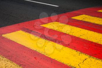 Pedestrian crossing road marking with yellow and red lines on asphalt