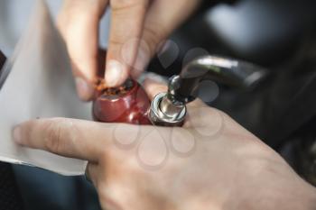 Man fills his pipe with tobacco, close up photo with selective focus on pipe