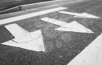 White arrows over black highway asphalt, pedestrian crossing road marking