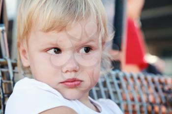 Outdoor close up portrait of displeased cute Caucasian blond baby girl