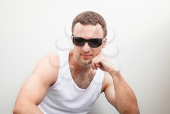 Portrait of Young sporty Caucasian man in white shirt and black sunglasses 