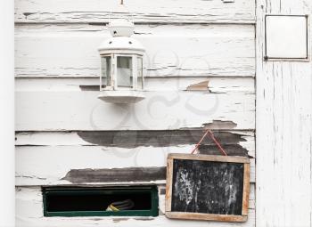 White rural wooden wall with black chalkboard, candle lamp and mailbox hole, background photo texture