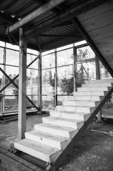 Generic industrial building is under construction. Interior fragment with unfinished concrete stairway, black and white photo with selective focus