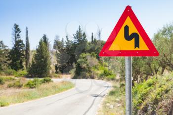 Double bend, triangular yellow warning roadsign with red border and black bent arrow