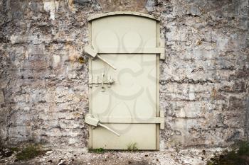 Locked massive metal door in old fortification wall, background texture