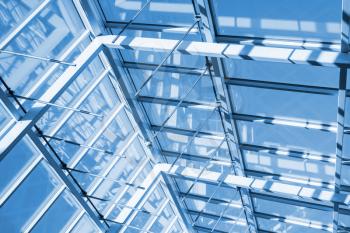 Abstract contemporary high-tech architecture background, internal structure of glass roof arch with lockable windows sections. Blue toned photo