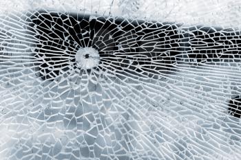 Broken strained glass with bullet hole and craks. Close-up background photo texture
