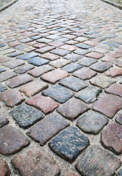 Old dark colorful shining cobblestone road, vertical background photo
