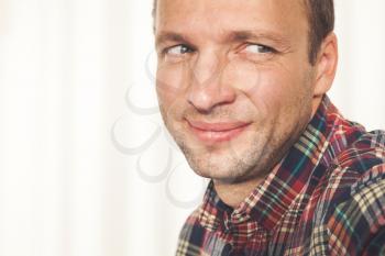 Close-up studio portrait of smiling young adult Caucasian man in colorful casual shirt