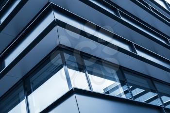 Corner of modern building facade, abstract fragment, shiny windows in steel structure, blue toned photo background