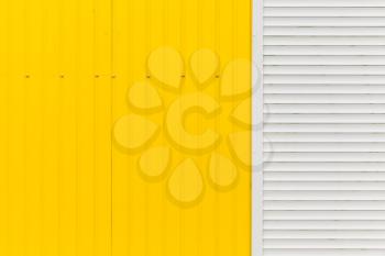 Corrugated yellow metal wall with white gate fragment, background photo texture