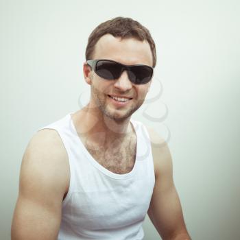 Portrait of Young sporty smiling European man in white shirt and black sunglasses, vintage toned square photo