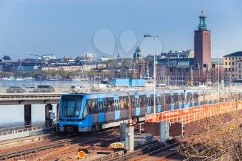Cityscape of Gamla Stan city district in central Stockholm with blue subway train going on bridge