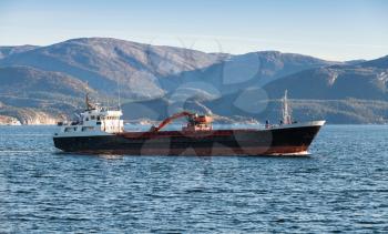 Industrial ship with excavator on deck goes on Norwegian sea, Trondheim region