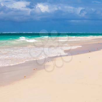 Caribbean beach, square background. White sand, azure shore water under cloudy blue sky. Dominican republic, Saona island