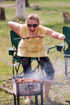 Woman grilling and eating shish kebab outdoor