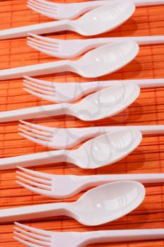 Orange plastic forks and spoons on the orange table
