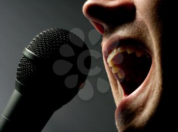 Close-up of man singing to microphone in dark