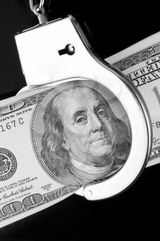One hundred dollar banknote in handcuffs. In B/W