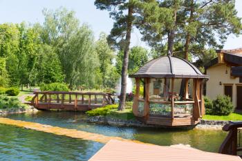 Beautiful pond in spring park with wooden summer-house