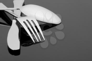 Side view of silver fork, knife and spoon on gray background