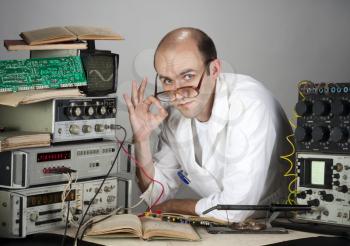 Pensive scientist working at vintage technological laboratory. Showing OK sign