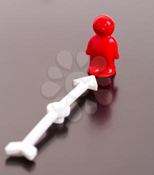 Red toy man and arrow on glossy background