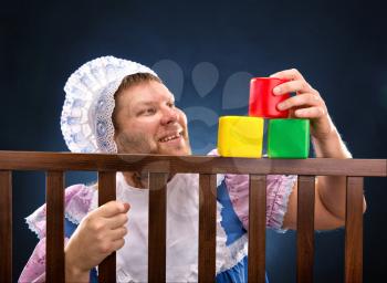 Man weared as baby playing in playpen