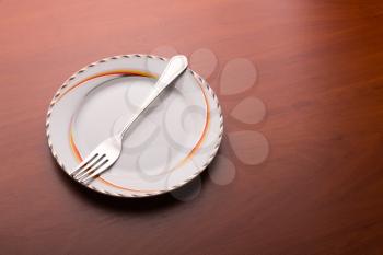 White plate and fork on wooden background