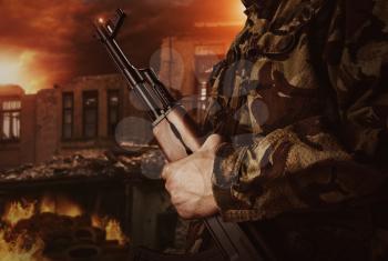 Soldier is holding gun on apocalyptic dark background