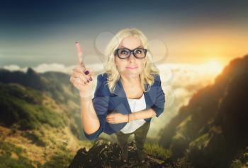 Blonde businesswoman in glasses pointing with her finger stands in the mountain