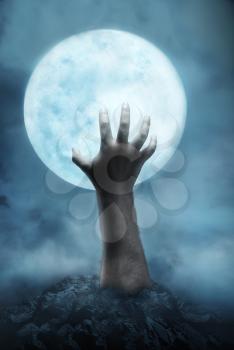 Creepy hand rising from the hole to the moon at night